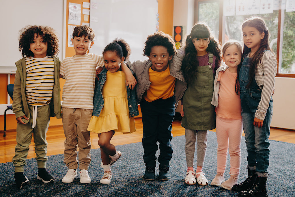 Disability related language at school: a  color photo of a seven children of diverse backgrounds standing together for a photo 