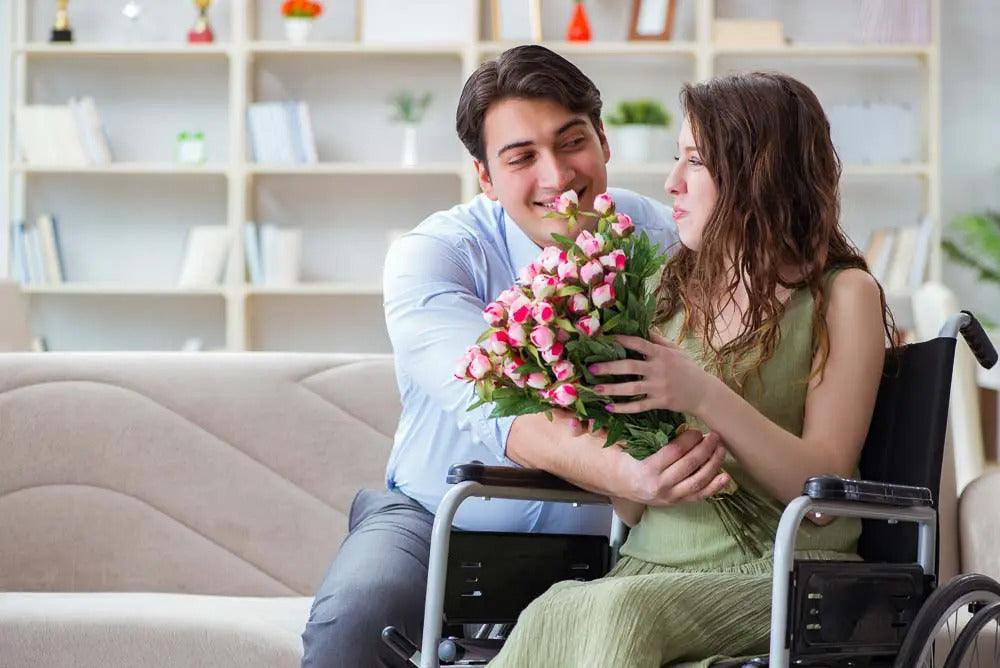 Image for article on dating disabled woman. Man tightly hugs woman in wheelchair around the waist. (Almost smothering). He looks like one of those really sweet guys, but too sweet. The woman is holding flowers and looks sideways and back to the man.