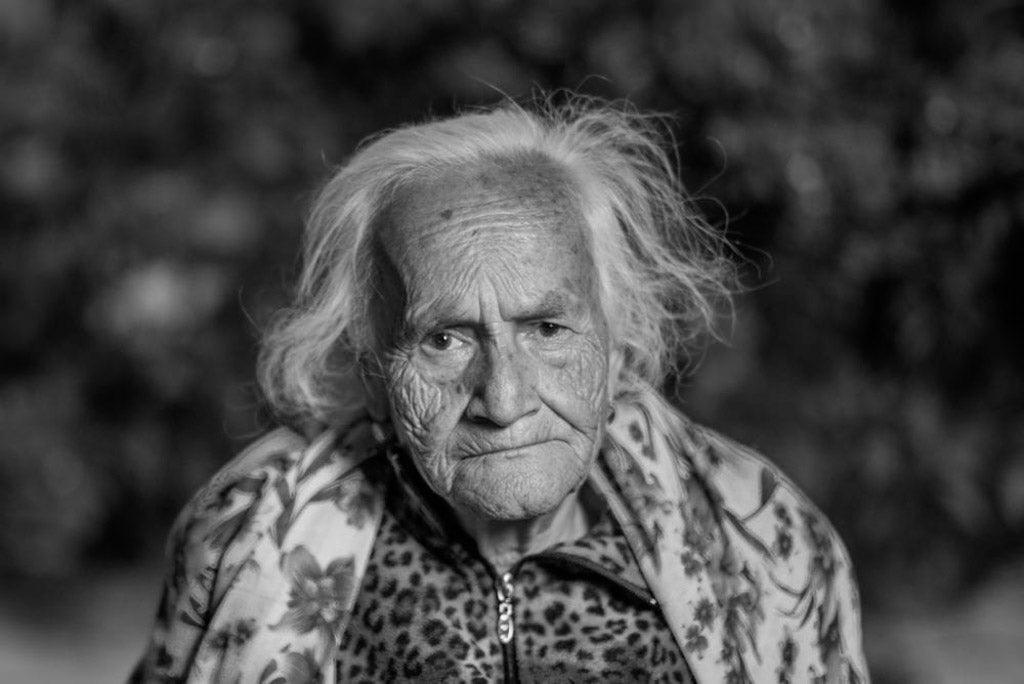 Image for article on ageism in healthcare. A black and white portrait photo of an older woman from Yuriria, Mexico. She is heavily wrinkled with a wise expression. Her face stares intensely at the camera.