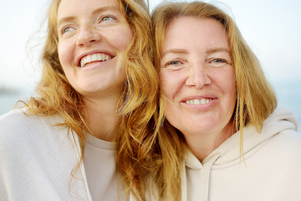 A close-up photo of a mother and her adult daughter laughing together.