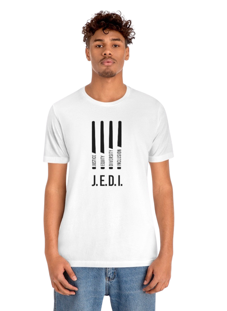 This is a photo of a white JEDI t-shirt. In the middle of the front of the JEDI t-shirt, are four black lightsabers. At the bottom of each saber representing the saber handle is one word: Justice Equity Diversity Inclusion. Beneath the sabers is the acronym JEDI in black upper case letters.