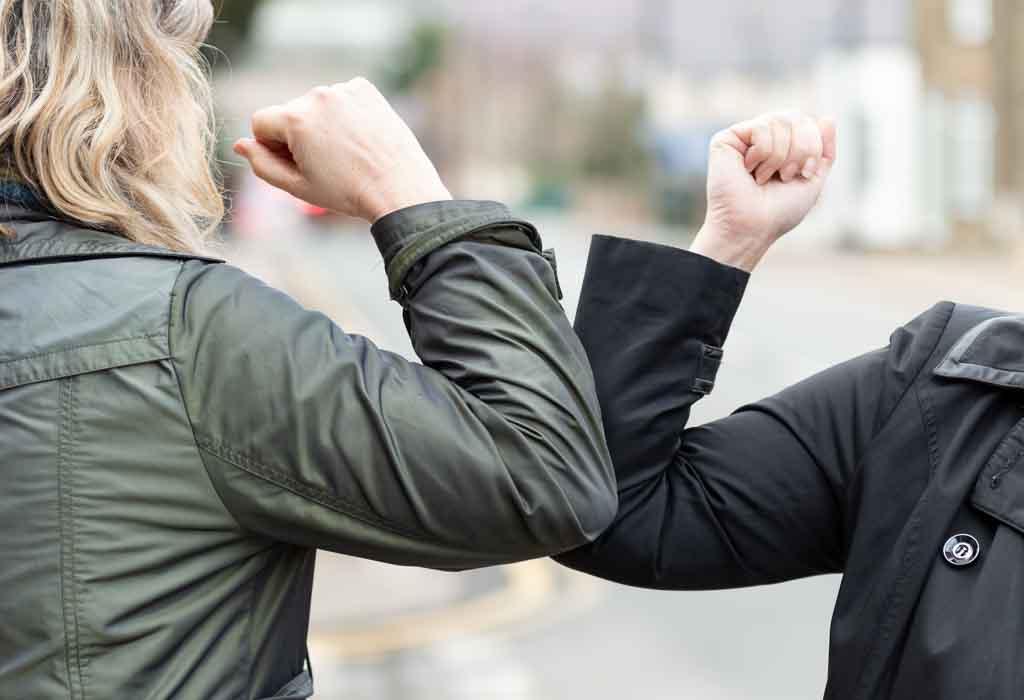 Picture of an elbow bump. New novel greeting to avoid the spread of coronavirus. Two women friends meet in a British street with bare hands. Instead of greeting with a hug or handshake, they bump elbows instead.