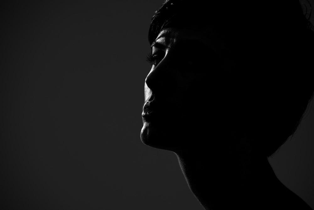 Very dark portrait silhouette portrait of short hair woman looking at camera