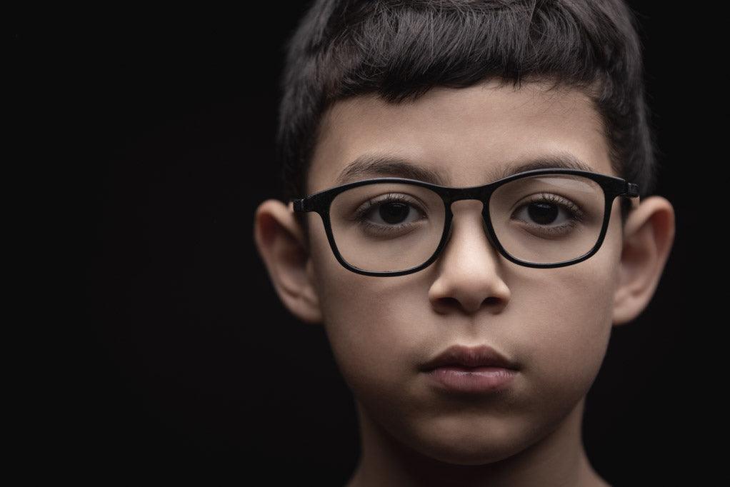 Out of the mouth of babes and sucklings- a photo of boy looking intently at the camera. He is wearing glasses.