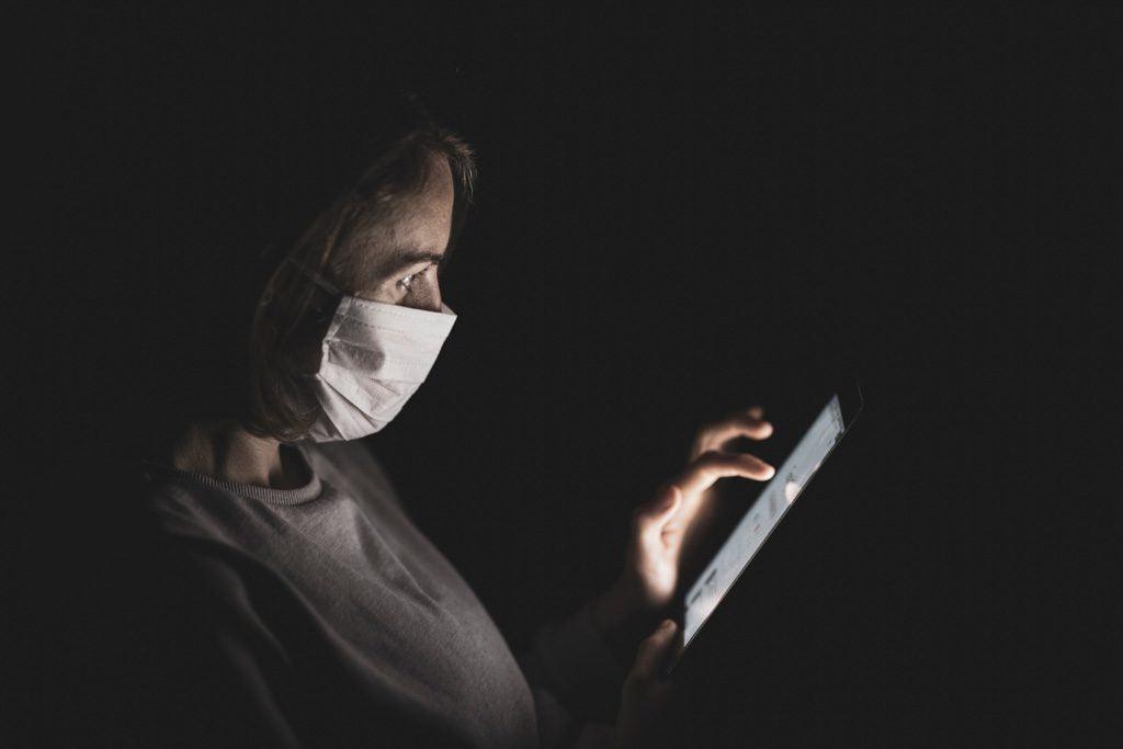 Photo of a person using a mobile phone while wearing a mask.