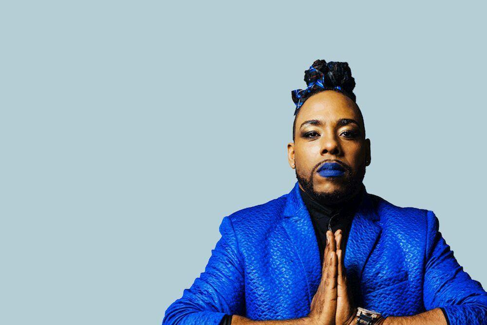 Image for article: We need to listen to young disabled LGBT+ people. A teenage person, wearing a bright blue jacket and blue lipstick, has their hands clasped together in a prayer like pose.