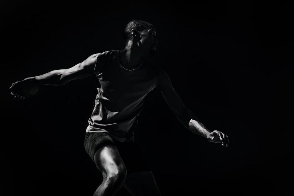 Dark dramatic composite photo of man throwing a discus for an article: 'athletes talking about mental health matters'