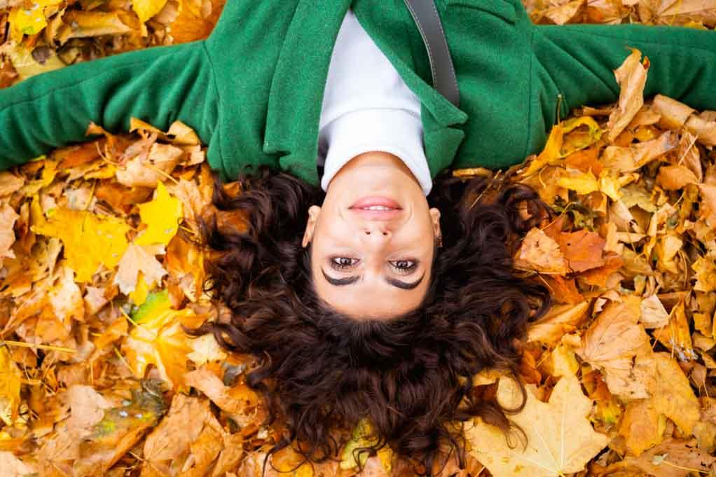 My daughter was diagnosed with cerebral palsy: image of a woman relaxing on soft yellow leaves on the ground and smiling