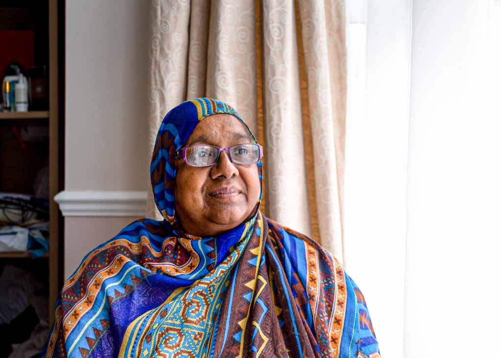 Article on being a disabled parent: a photographic portrait of Sarifa Patel sitting next to the window in her living room