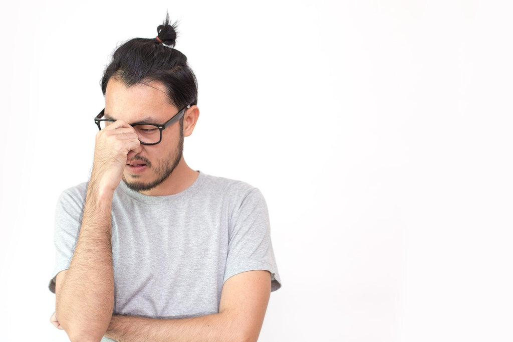 Photo of an article on what not to expect from a colonoscopy. Image is of closeup portrait of asian man with a headache on white background.