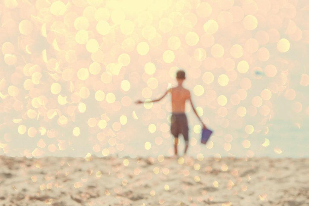 Photo for an article: my child was recently diagnosed as disabled. Picture of young child at the beach, defocused image with intense sunshine.
