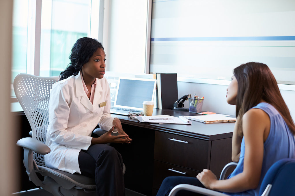 A photo of a Black female doctor talking to a white female patient: cancer questions doctors never answer