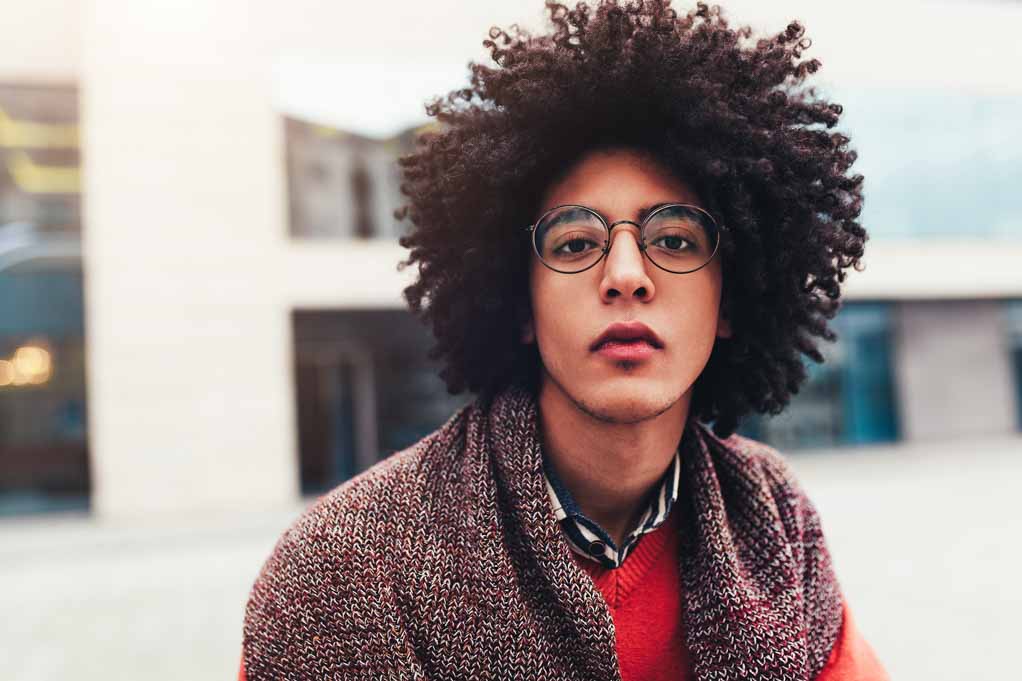 Non-Hodgkins Lymphona stories: close-up portrait of a young handsome Egyptian person with curly hair with a serious expression.