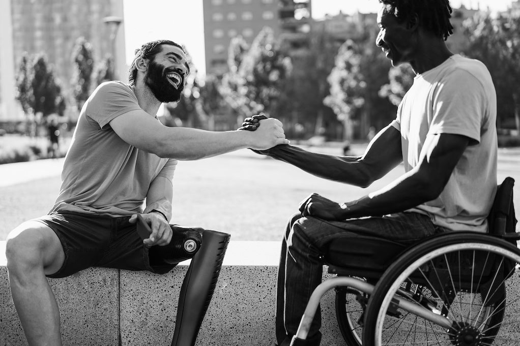 Disabled people don't need to be fixed: Multiethnic disabled friends greeting each other in a city park.