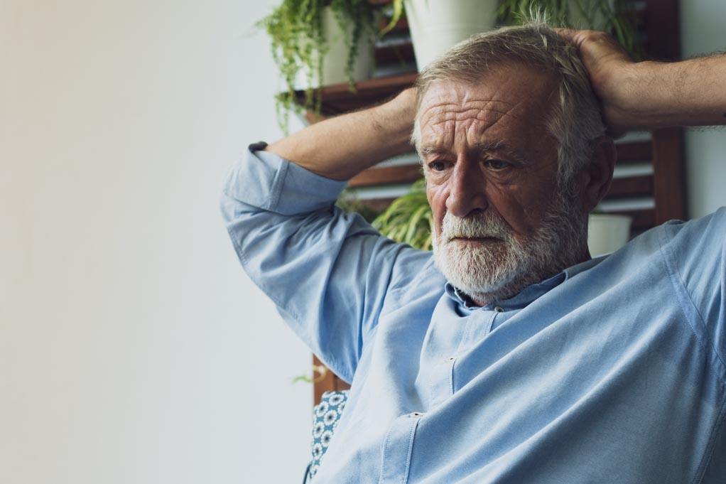 Does stress affect men more than women? A photo of an older man looking serious and stressed on balcony.