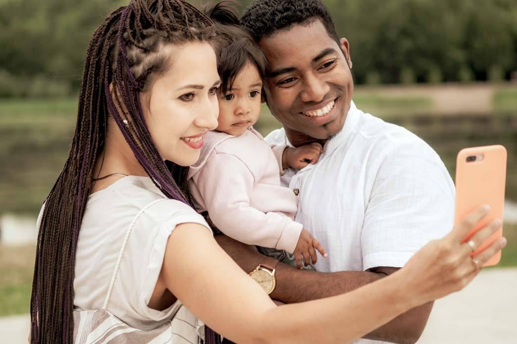 Two adults and a child pose together for a phone photograph.