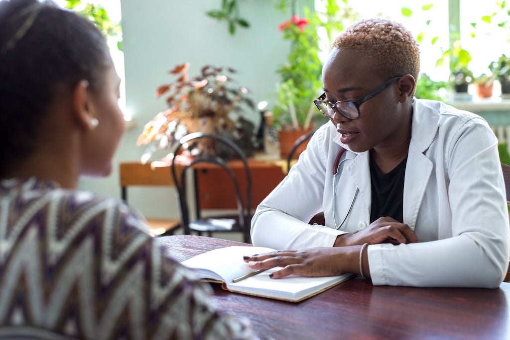 Racial disparities in patient-provider communication. A color photo of a doctor and patient having a conversation over a desk.