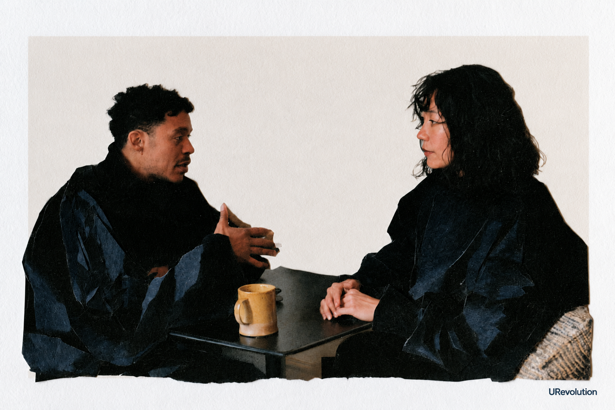 Cut-paper illustration of two adults talking across a small table with a yellow mug, one speaking while the other listens.
