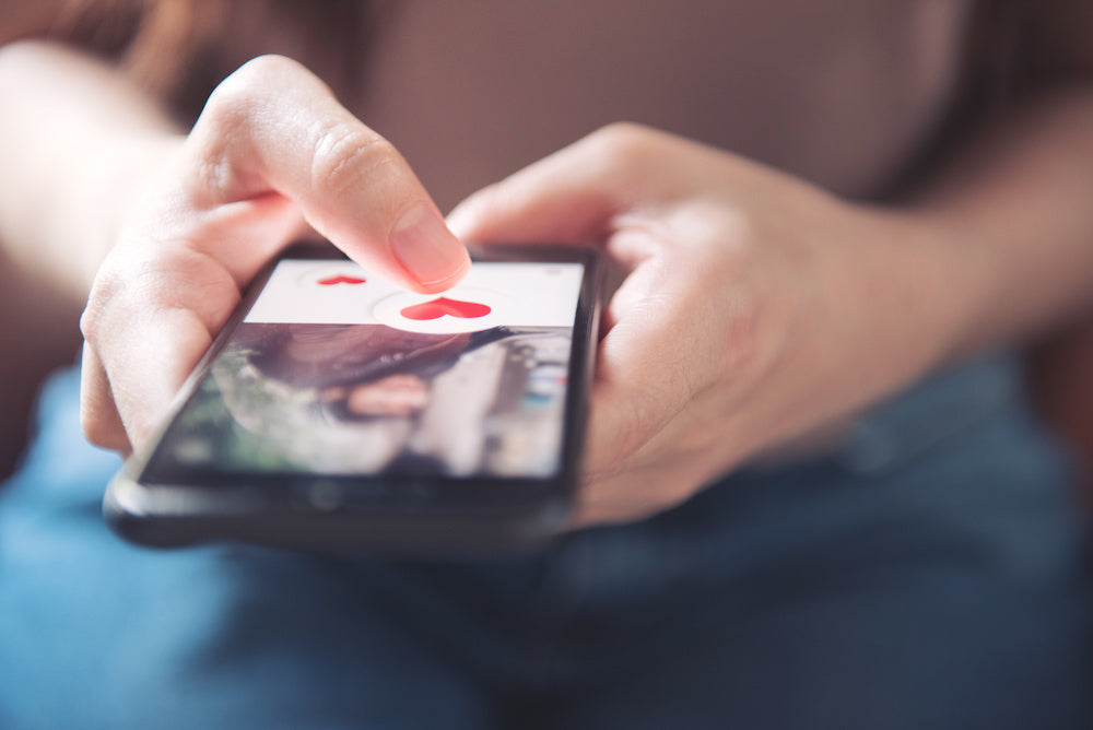 Finding love online when you have mental illness: photo of a finger of woman pushing heart icon on screen in mobile smartphone application.