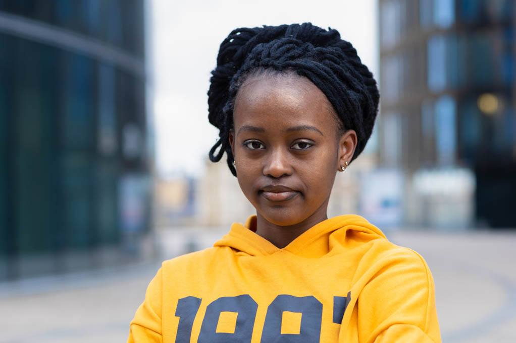 Growing up with Charcot-Marie-Tooth Disorder. Portrait of a calm confident fashionable young Black woman with dreadlocks wearing a yellow hoodie.