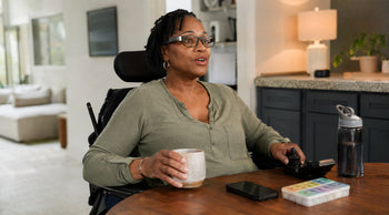 Disabled woman using a power wheelchair and smart glasses to control technology hands-free at home.