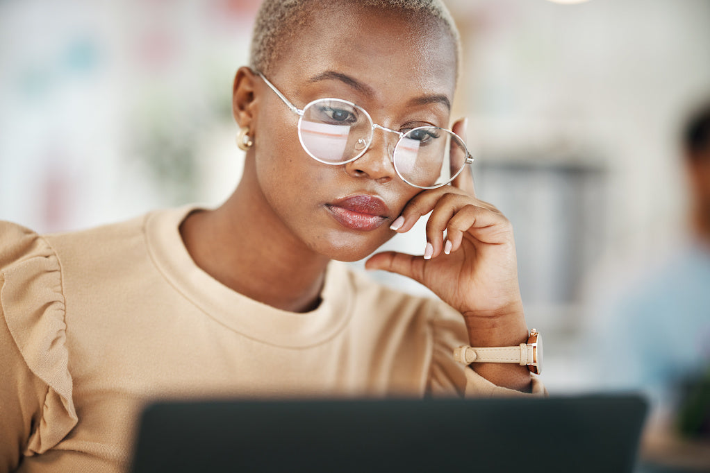Woman reading an email on a laptop with a thoughtful expression.