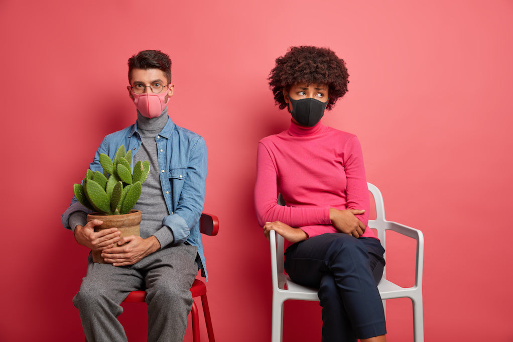 How to cope with a sick spouse: photo of two spouses sitting in a room separated. They are wearing masks and looking away from each other.  
