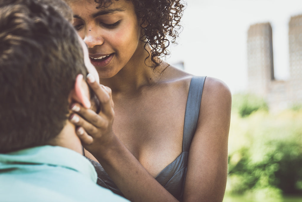 How to discuss vaginismus with your partner: photo of a woman lovingly holding their partner's face in their hands. Smiling. Outdoors.