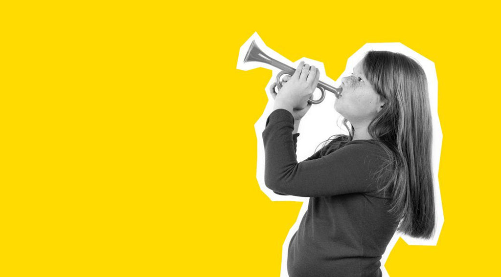 How to help kids with obesity- a side profile photo of red-haired child playing music on pipe (trumpet). Portrait is isolated on a yellow background.