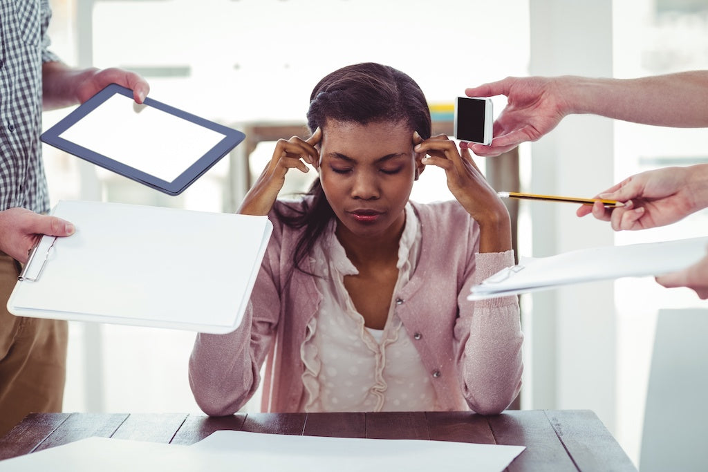 A woman is sitting at her desk, looking stressed, thinking to themselves "I think I have ADHD."