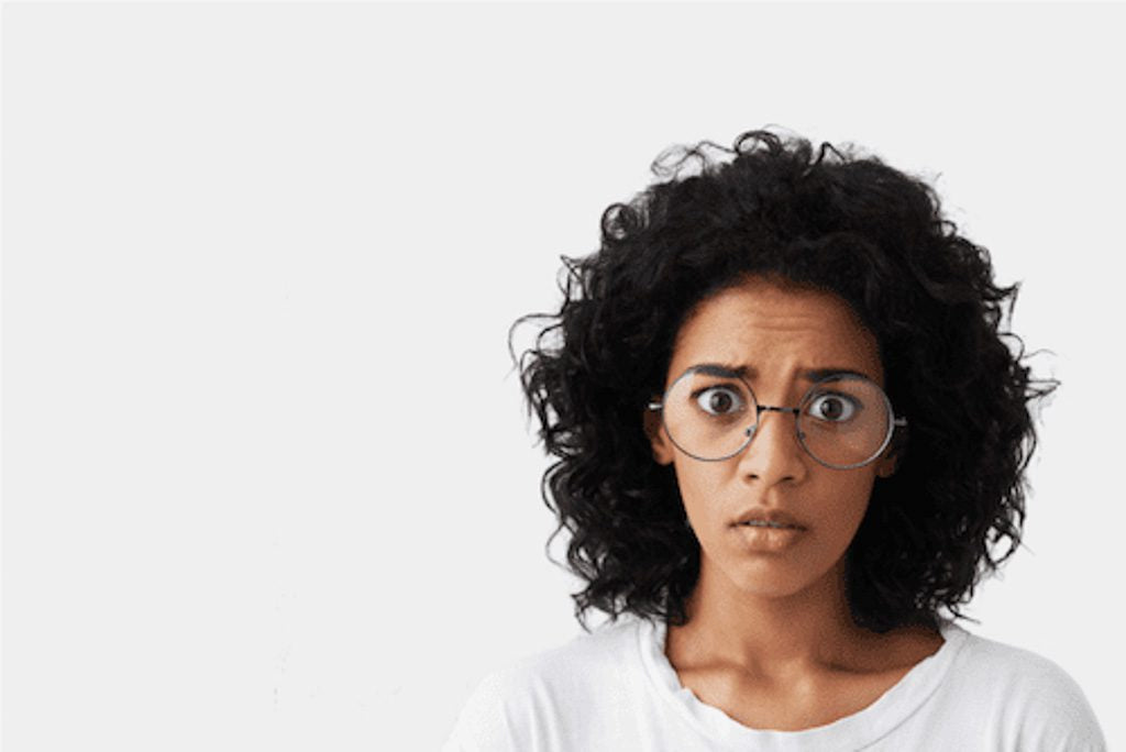 Anxious, worried woman with glasses looks straight at camera. She has dark short hair and wears glasses and a white t-shirt. She is thinking to herself: 