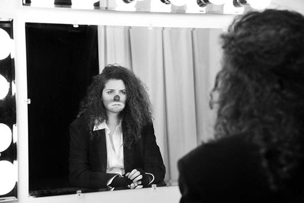 Black-and-white portrait of a woman looking into a lighted mirror.