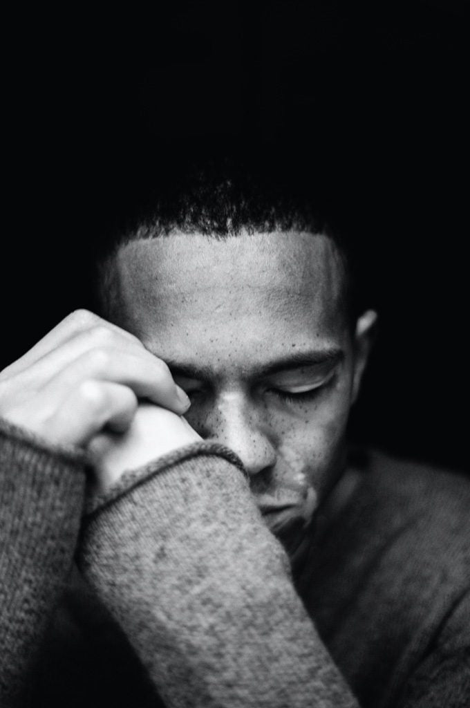A black and white photo of a young man thinking about dating with vitiligo. His eyes are closed and his vitiligo is clearly visible.