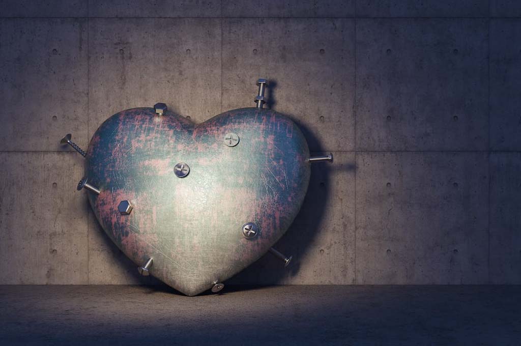 How to cope with a chronically ill spouse? Photo of an industrial style shot of a metal heart with nails and screws poking out, against a dark industrial wall.