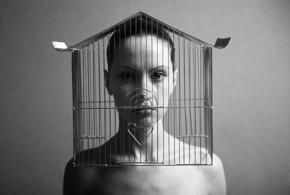 Short story about drug addiction: black and white surrealistic portrait photo of a woman with a cage over her head. Image for an article on drug addiction and homelessness.
