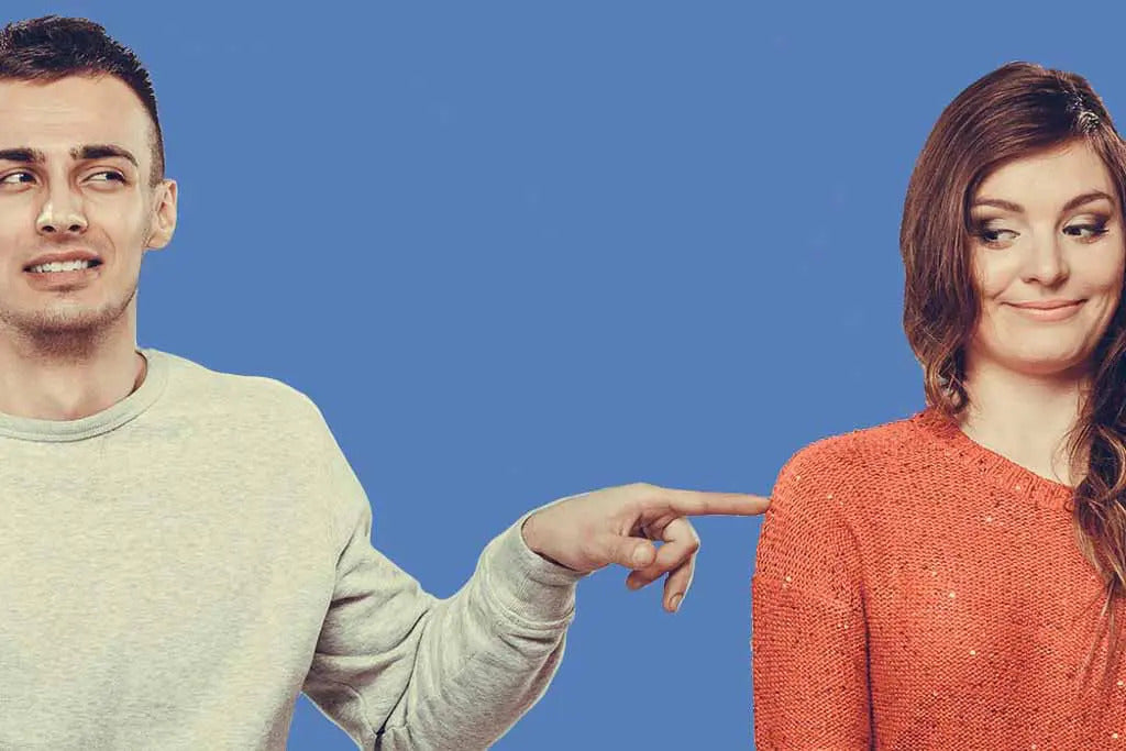 Photo for article about talking about poop in a relationship. Photo of two people on an awkward date. One person is pointing accusingly at the other, who has an embarrassed look on their face.