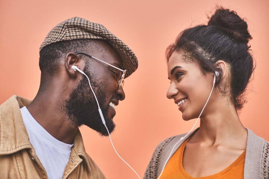 How to support someone with chronic illness: image of two friends listening to music smiling at each other.