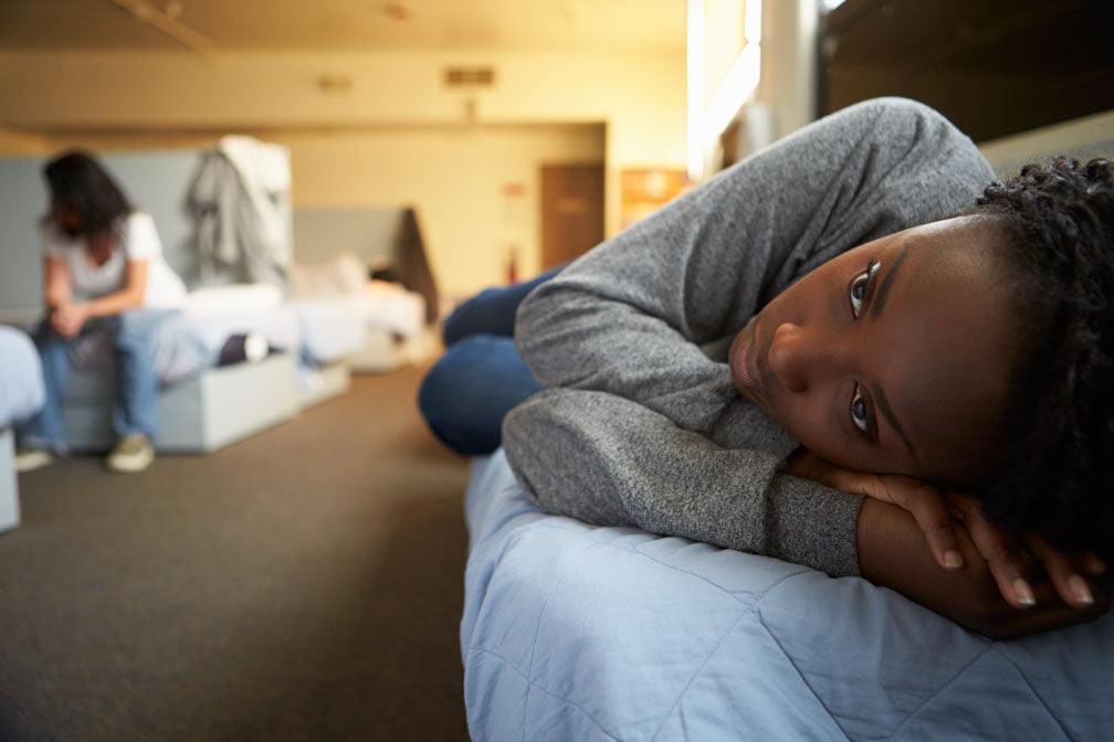 Common myths about homelessness: a color photo of the interior of a shelter for homeless people. A woman is lying on a bench awake.