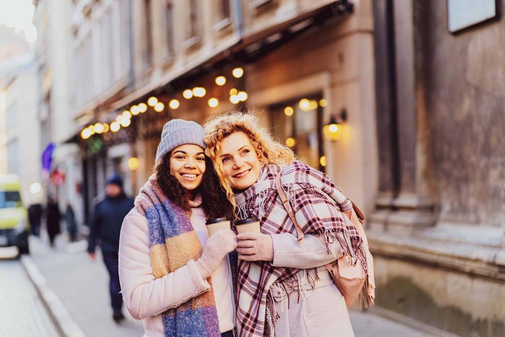 Help a friend with cancer by taking them shopping. A fashionable portrait of two cheerful women walking in the city in winter.