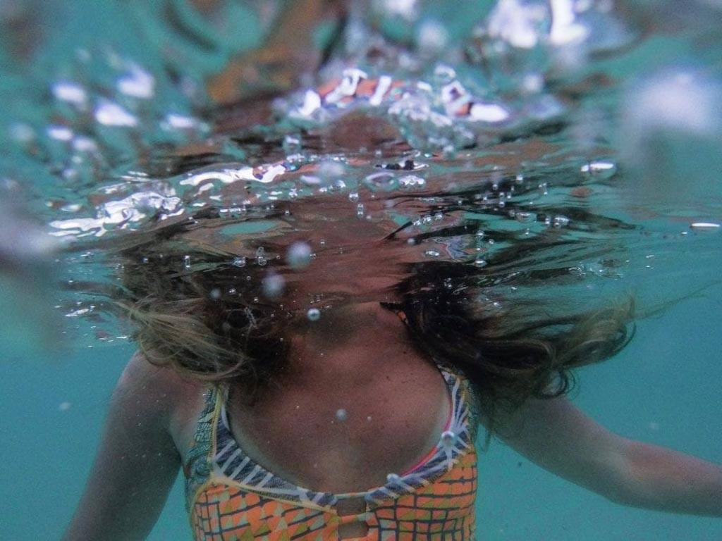 Dissociative identity disorder misconceptions: a person's torso is visible beneath water while their head is blurred by bubbles and ripples on the surface.