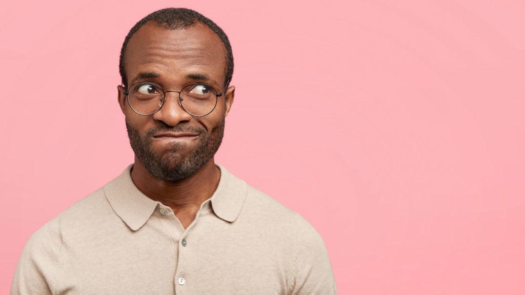 Crohn's disease horror stories: the one where I pooped myself. A photo of hesitant dark-skinned unshaven male, they curve their lips, look aside, embarrassed because they pooped themselves.