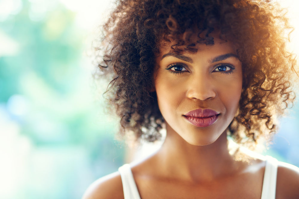 Image for an article on my mom has breast cancer what can I do. Close up portrait of young woman looking pensively at camera. She is a very subtle smile and her eyes are warm, yet show some pain.