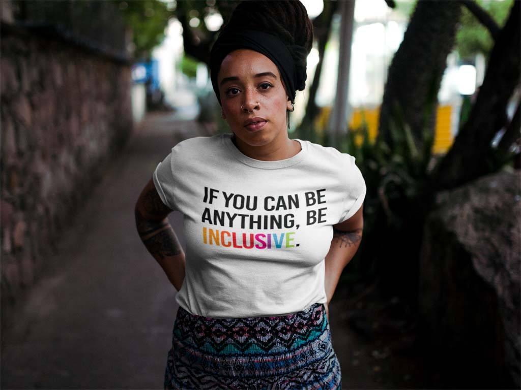 Anti-oppression psychotherapy: an African-American woman is standing on a path with her hands on her hips. She is wearing a white t-shirt with the phrase, 'If you can be anything, be inclusive,' printed on it.