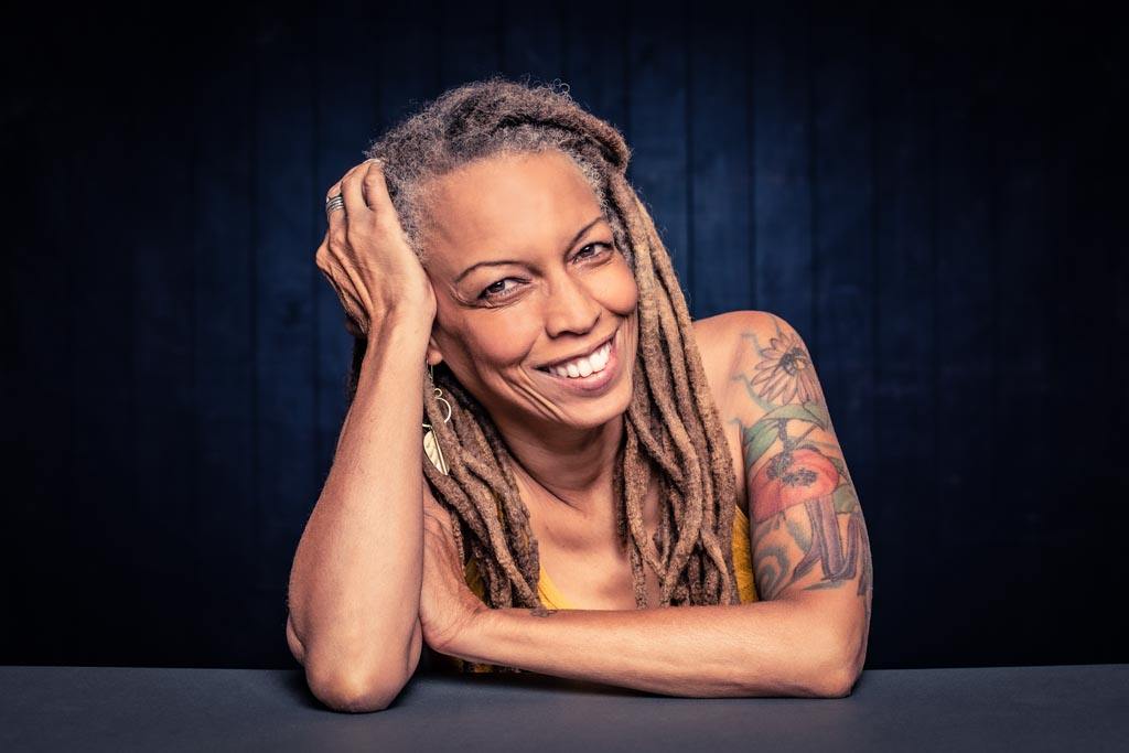 Close up photo of an African American woman with dreadlocks leaning on a table. Image for an article about growing up with a bipolar mother.