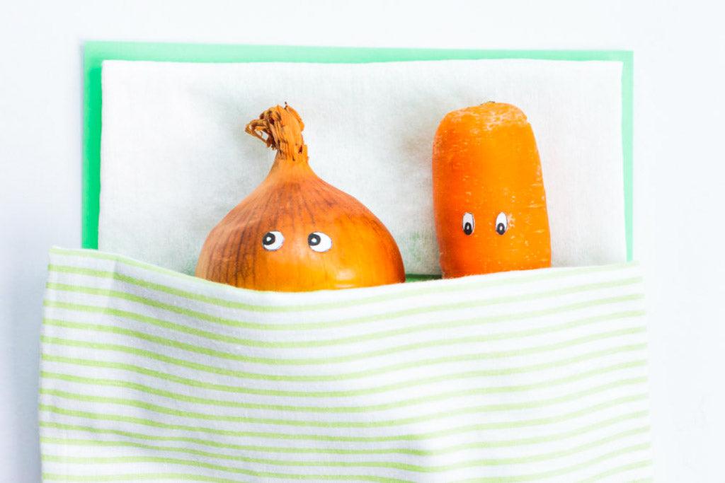 Sex after cancer treatment: photo of a carrot with a leek lying together in bed. Leek looks away uncomfortably while carrot looks down.