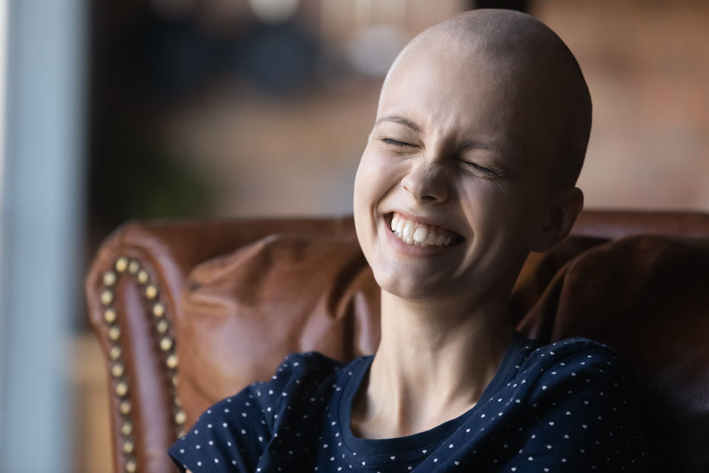 Close up of happy young sick woman with cancer laughing while reading funny personal cancer blogs.