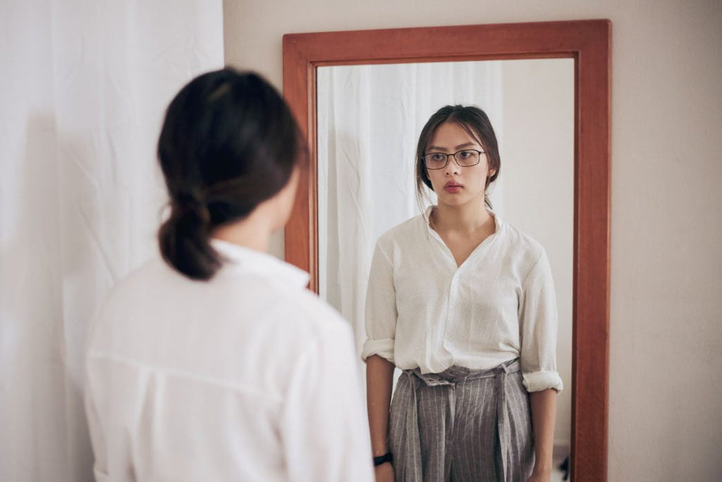 Overcoming family comparisons: a photo of a young woman staring at herself in the mirror