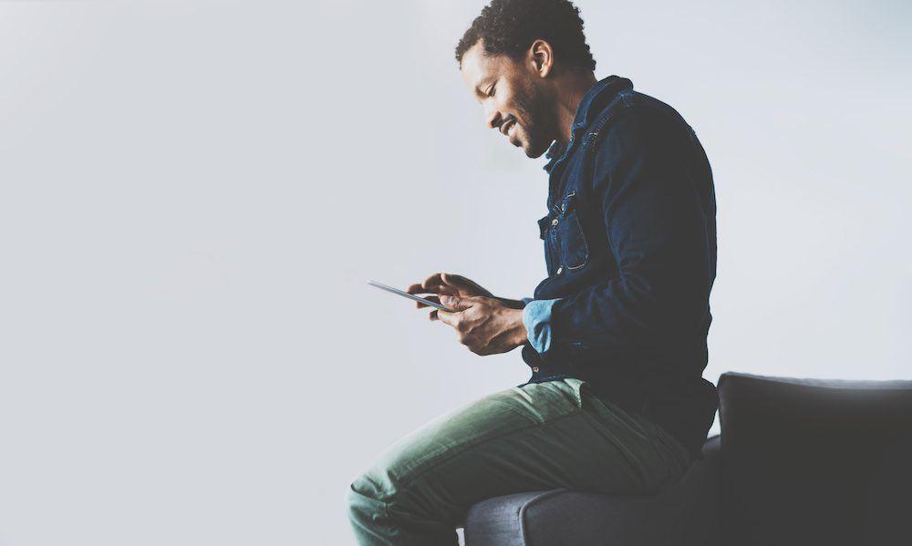A man sitting on a sofa using a tablet.