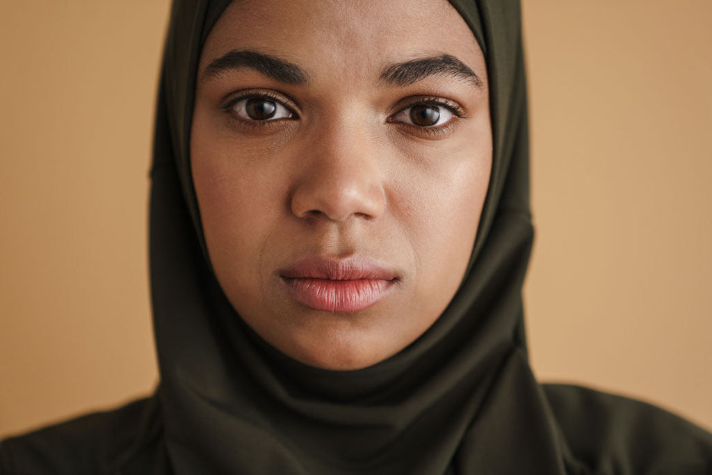 Undiagnosed female autism selective mutism: a Black woman in a hijab posing and looking at camera isolated over beige background.