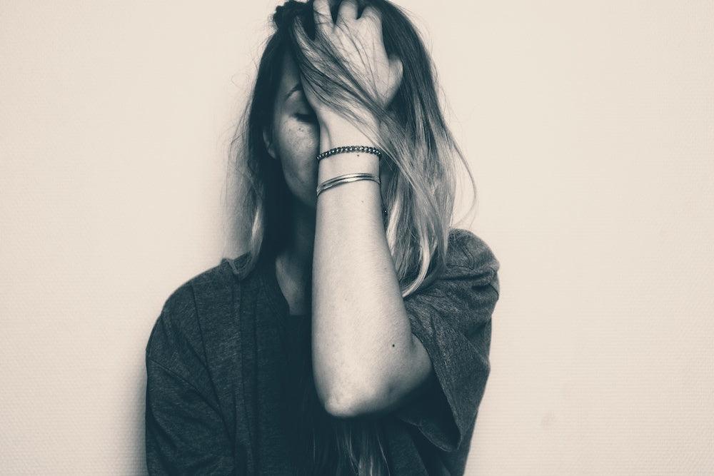 Photo for article on understanding bipolar disorder. Black and white grunge photo of person with long blonde hair holding their head in their hands. Person looks like Claire Danes in Homeland.